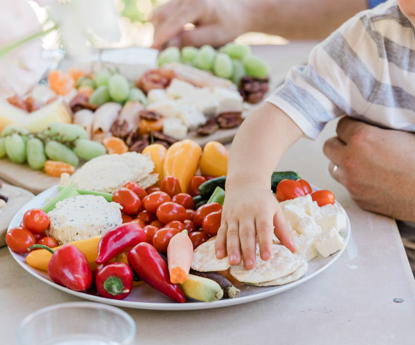 Mano de un niño cogiendo alimentos de un plato