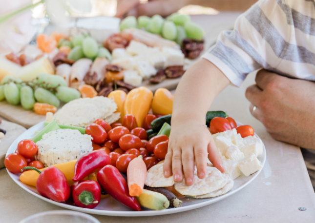 Mano de un niño cogiendo alimentos de un plato